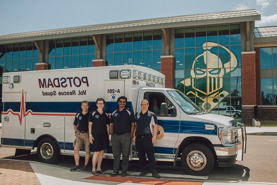 Potsdam EMS workers stand in front of their ambulance